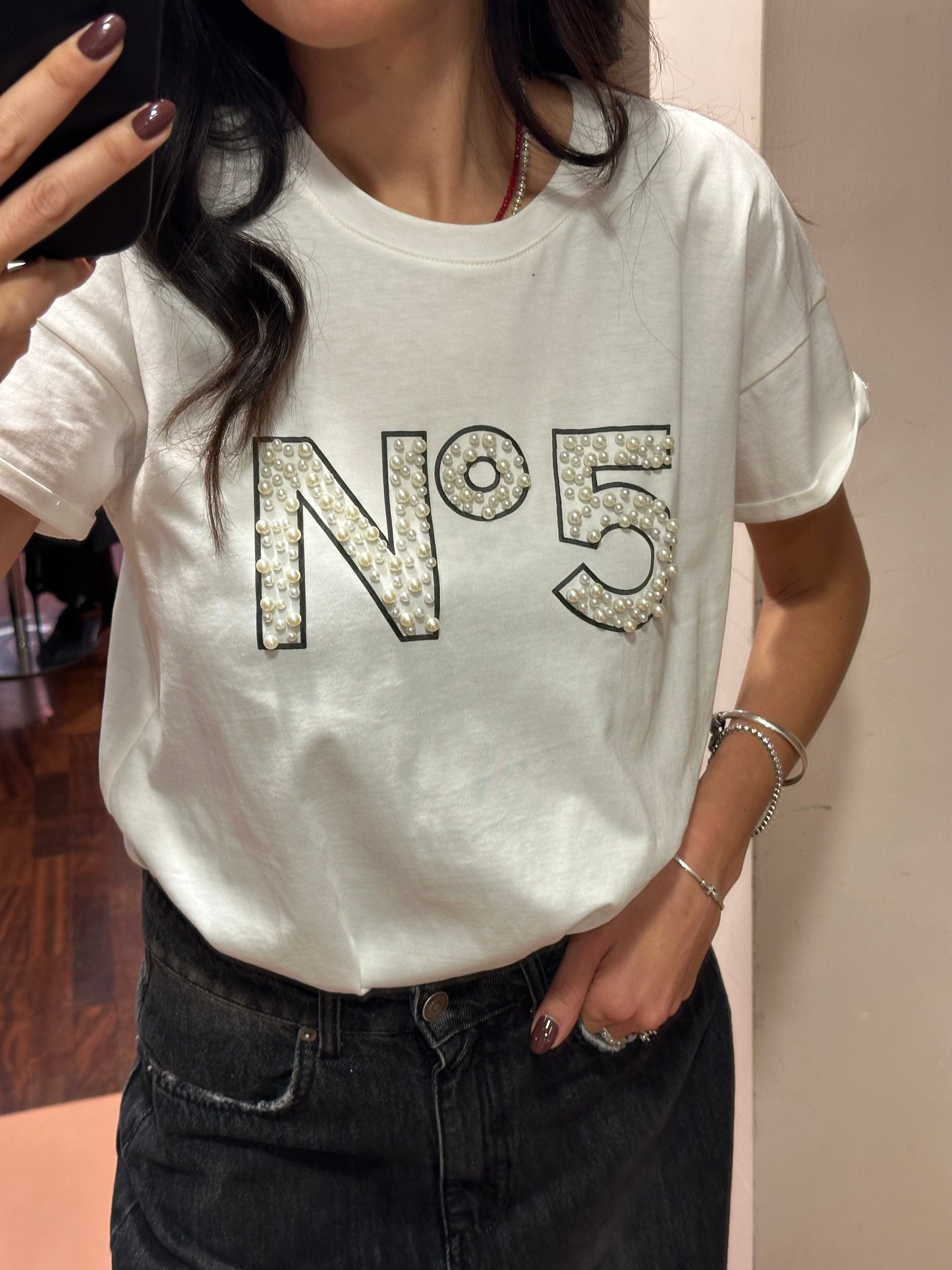 Tensione in t-shirt bianca con perle e scritta “N.5”