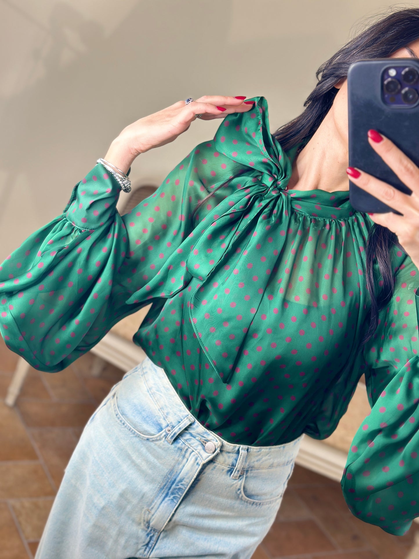 Tensione in blusa a pois con fiocco verde